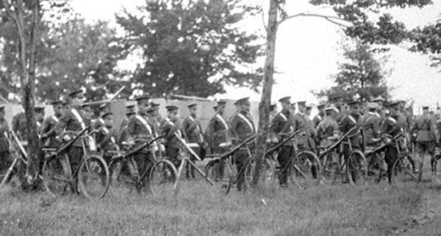 Line-up of cyclists parading next to the Autocars purchased by Brutinel. MilArt photo archives